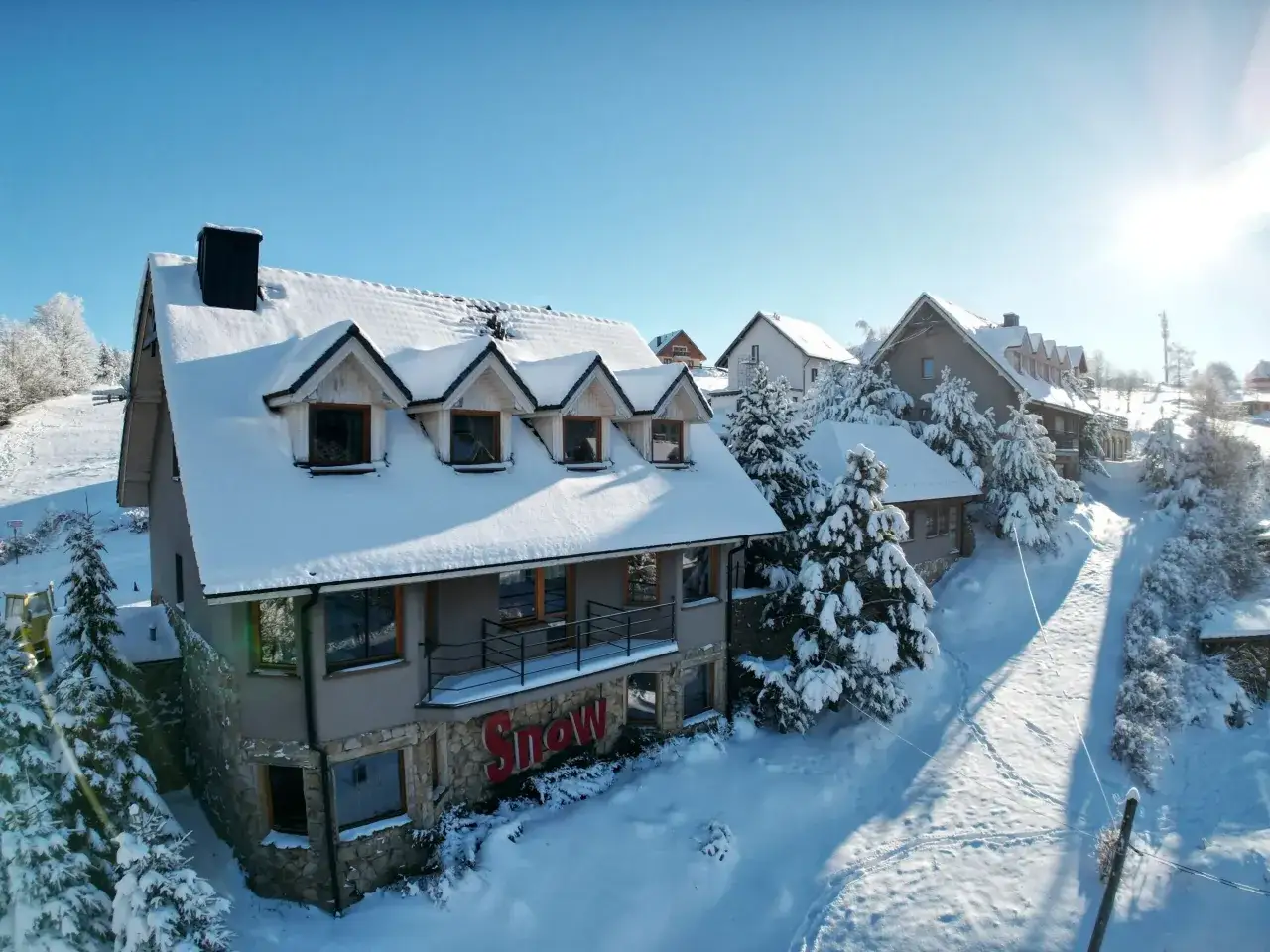 Zimowy hotel przy stoku narciarskim w Polsce, otoczony śniegiem i sosnami.