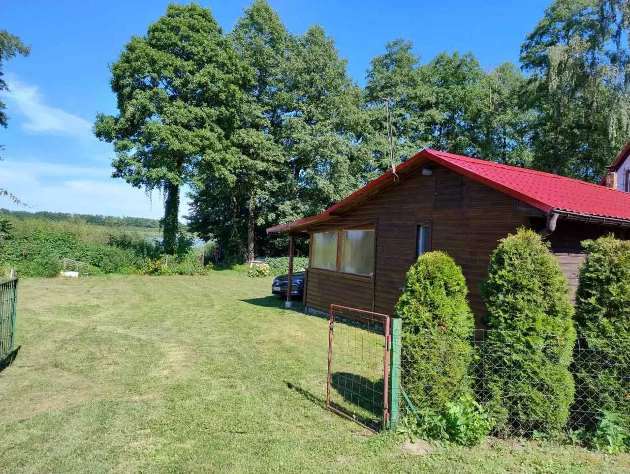 Idealne miejsce, gdzie na ryby z noclegiem. Drewniany domek z czerwoną dachem, otoczony zielenią i blisko jeziora.