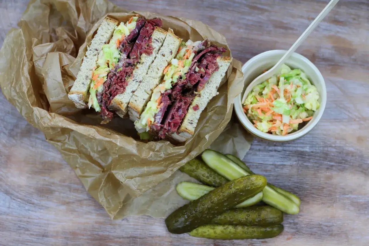 Pyszna kanapka z pastrami, pełna soczystego mięsa i chrupiącej sur&oacute;wki, podana z og&oacute;rkami konserwowymi.