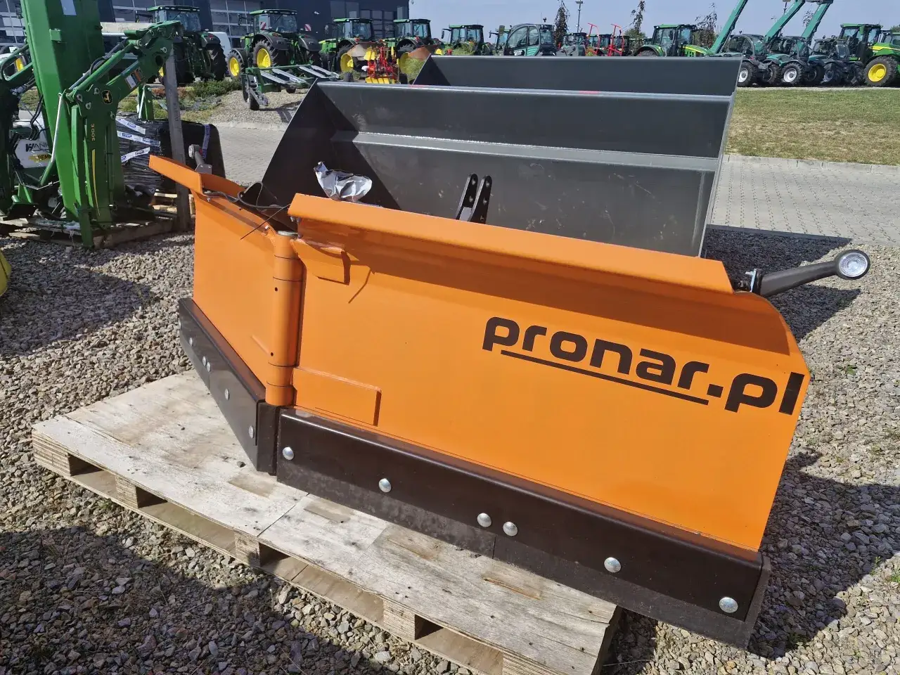 Pomarańczowy pług do odśnieżania Pronar. Gotowy do pracy zimą, czeka na śnieg.