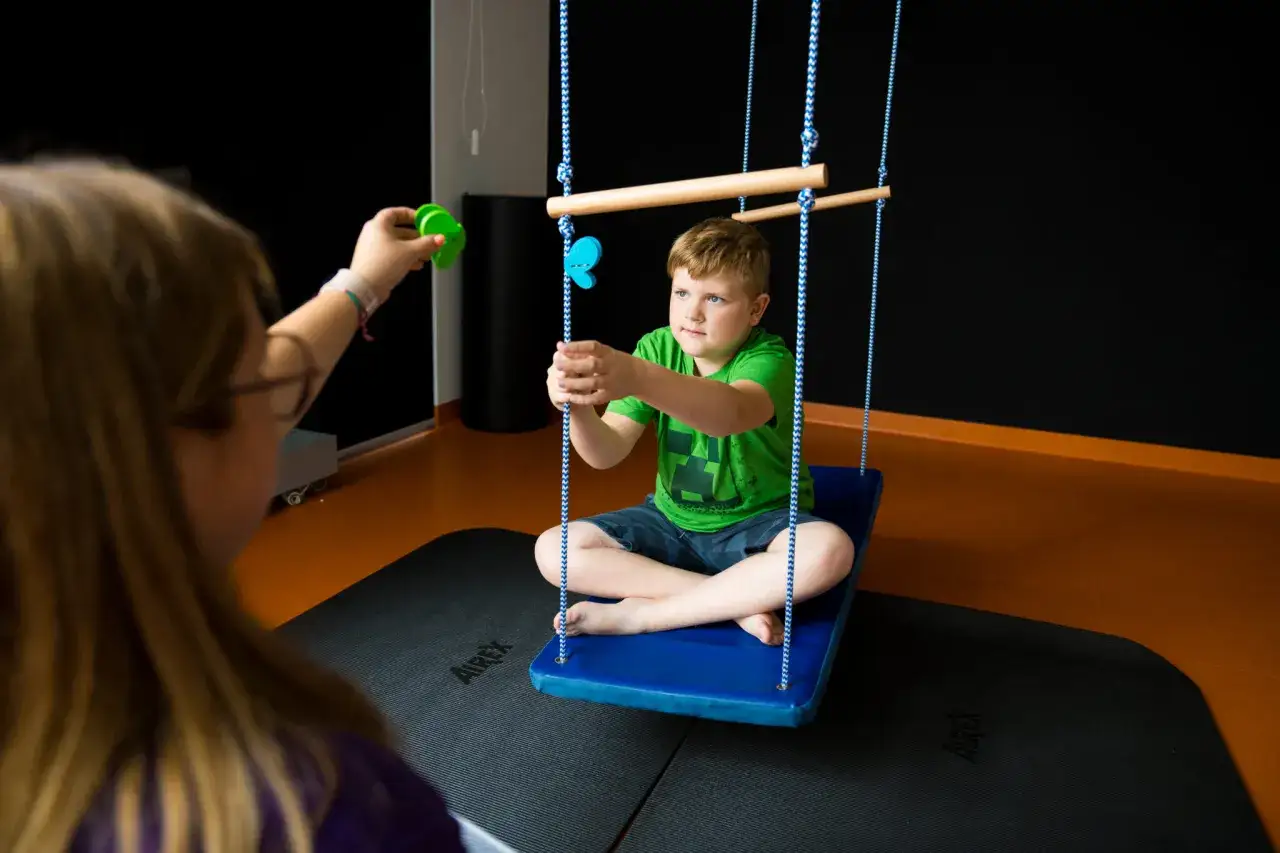 Dziecko na huśtawce sensorycznej uśmiechnięte