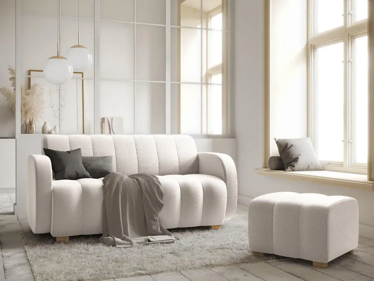 Jasny salon z puszystą kanapą i pufą, idealny do stworzenia harmonii w feng shui domu.