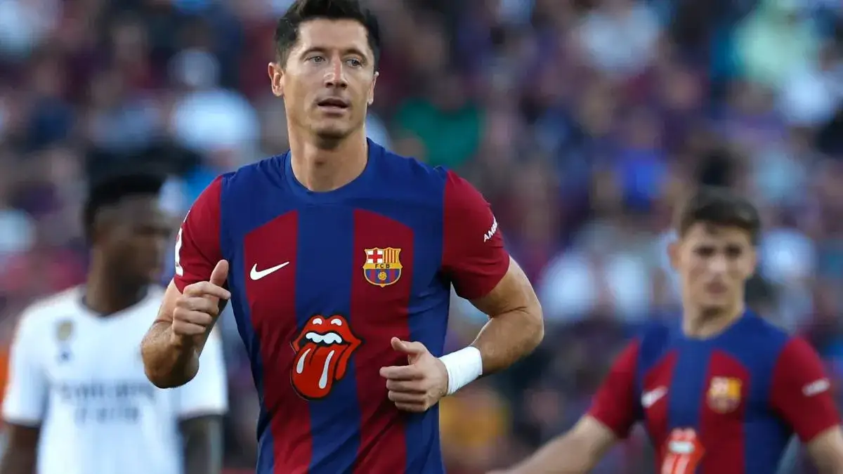 Robert Lewandowski w koszulce FC Barcelona, uśmiechnięty, z tłem stadionu lub miasta