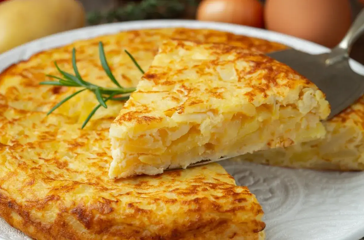 Pyszna frittata z ziemniakami, podana na talerzu, z gałązką rozmarynu. Idealna na obiad.