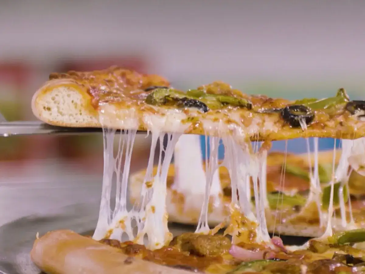 Rozciągający się ser z pizzy, kt&oacute;ra jest podnoszona łopatką. Czy pizza to fast food? Ta pyszna, gorąca pizza z pewnością kusi!