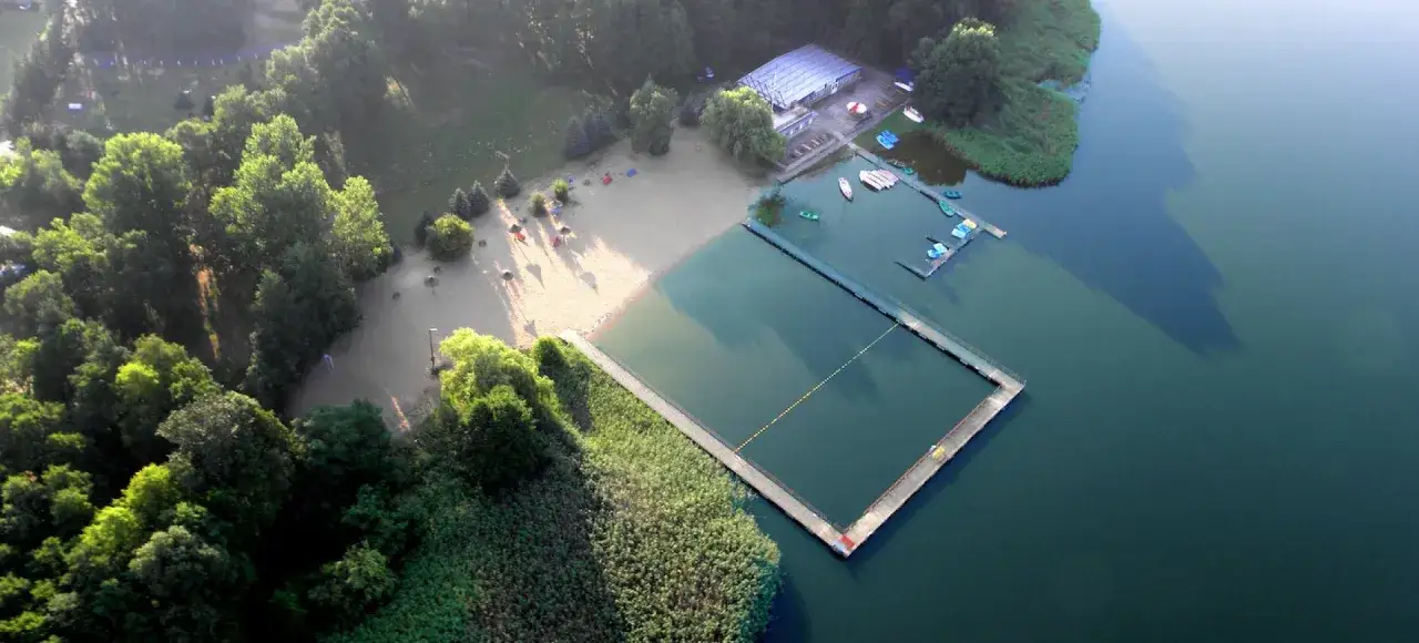 Malowniczy hotel nad jeziorem Wielkopolska. Plaża, basen, pomost i łódki zachęcają do wypoczynku.