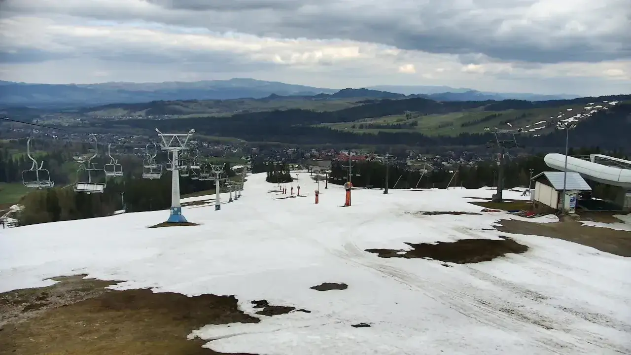 Widok na białka tatrzańska trasy narciarskie z wyciągami krzesełkowymi i ośnieżonymi stokami, w tle malownicze wzgórza.