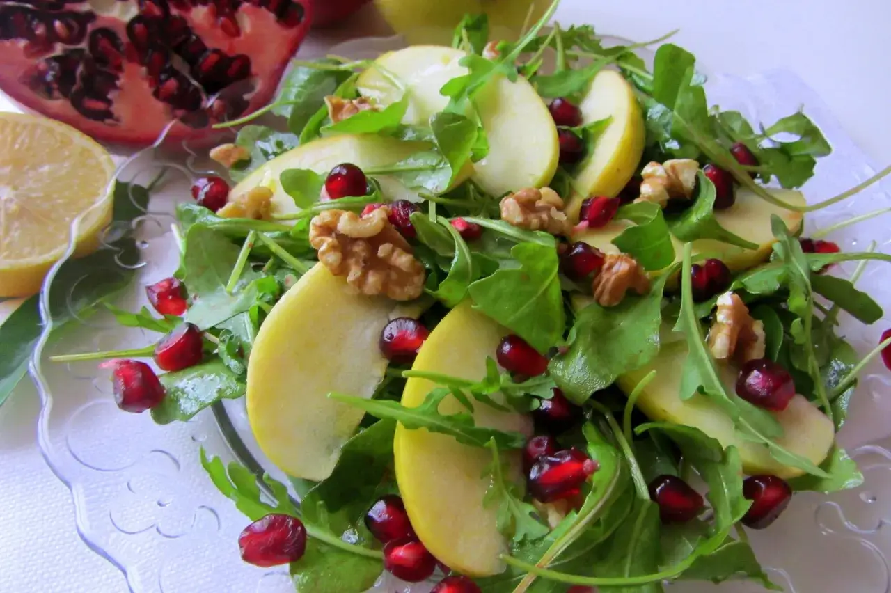 Sałatka z rukolą, jabłkiem, granatem i orzechami. Aby rukola nie była gorzka, dodaj do niej słodkie składniki, jak jabłko i granat.