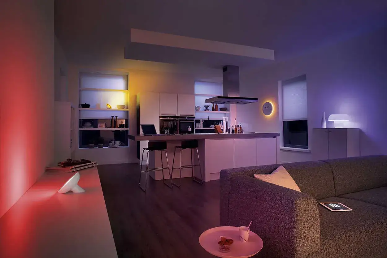 Nowoczesna kuchnia i salon z kolorowym, energooszczędnym oświetleniem LED. Wygodna sofa i wyspa kuchenna tworzą przytulną atmosferę.