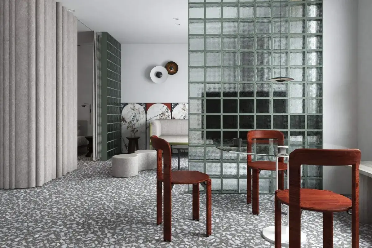 Nowoczesne wnętrze z luksferami zamiast okna, tworzącymi zieloną ścianę. Drewniane krzesła i szklany stolik.