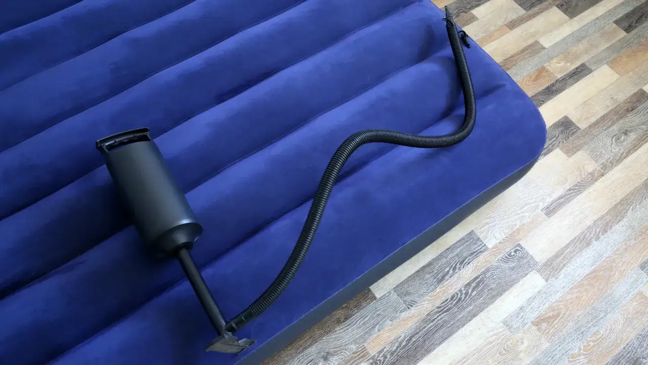 Ręczna pompka podłączona do dmuchanego materaca. Szybki sposób, jak napompować materac bez pompki elektrycznej.