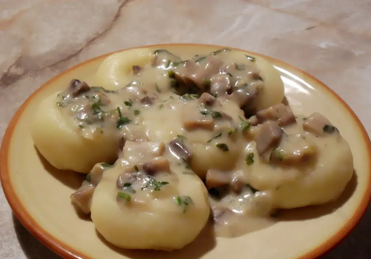 Sos pieczarkowy na talerzu z kluskami śląskimi