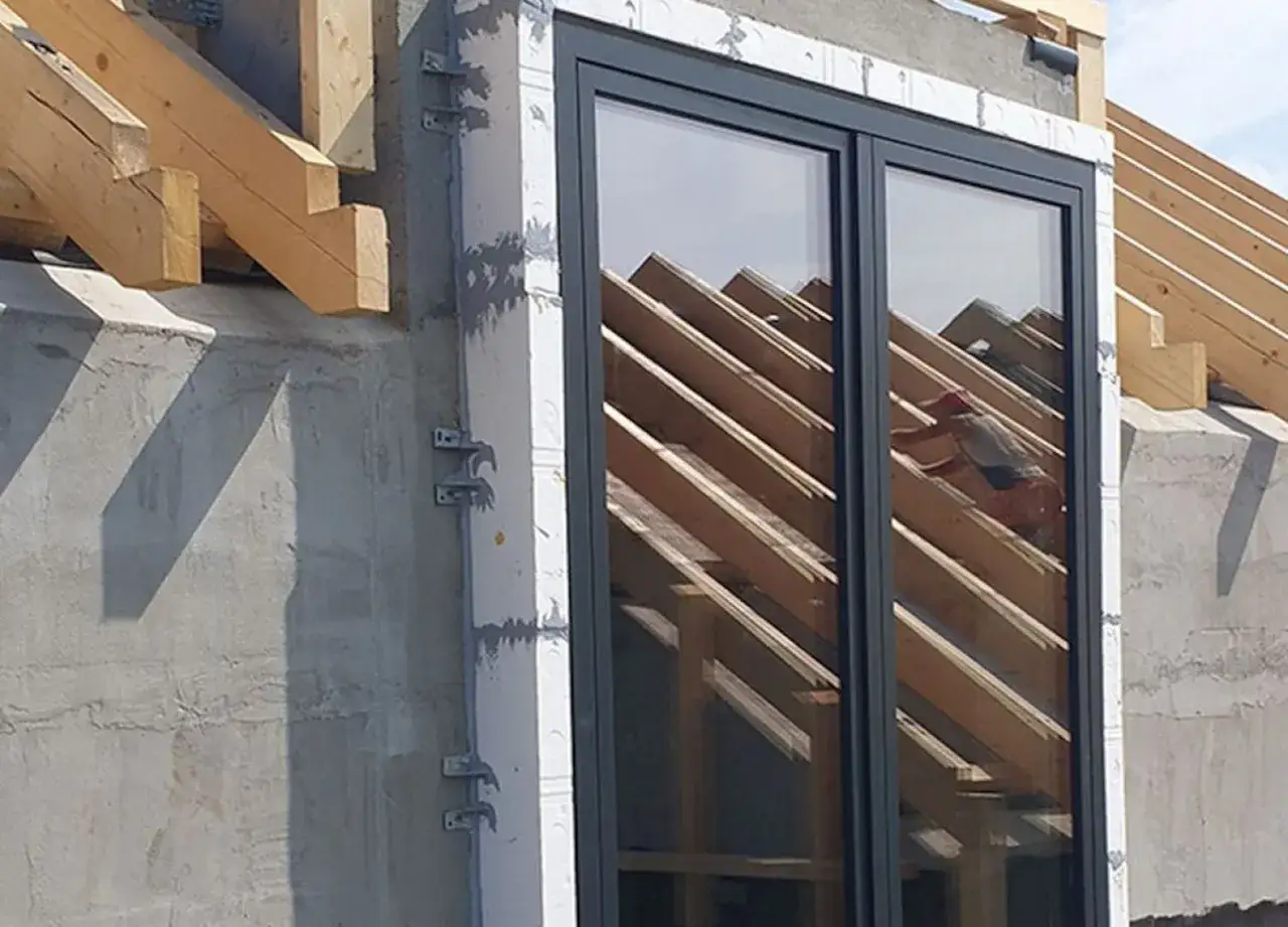 Nowe okna zapewnią czyste powietrze w domu. Montaż okien na budowie, widoczna konstrukcja dachu.