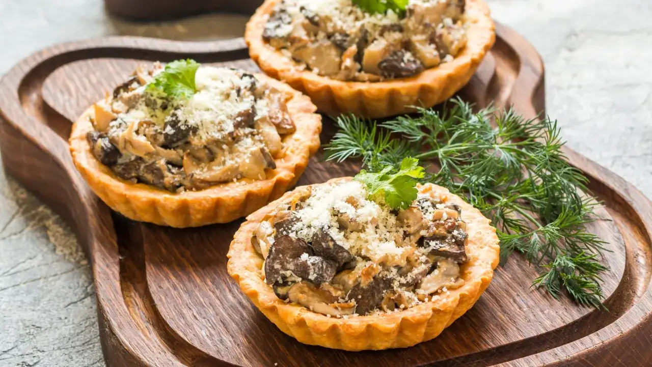Trzy tartaletki z nadzieniem grzybowym, posypane parmezanem i natką pietruszki. Idealne ciasto kruche słone na przekąskę.
