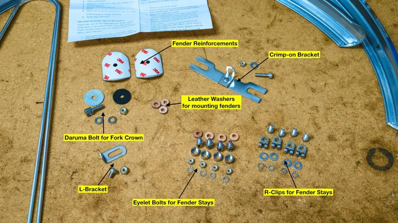 Zestaw do montażu błotnika rowerowego: śruby, wsporniki, podkładki sk&oacute;rzane i wzmocnienia.