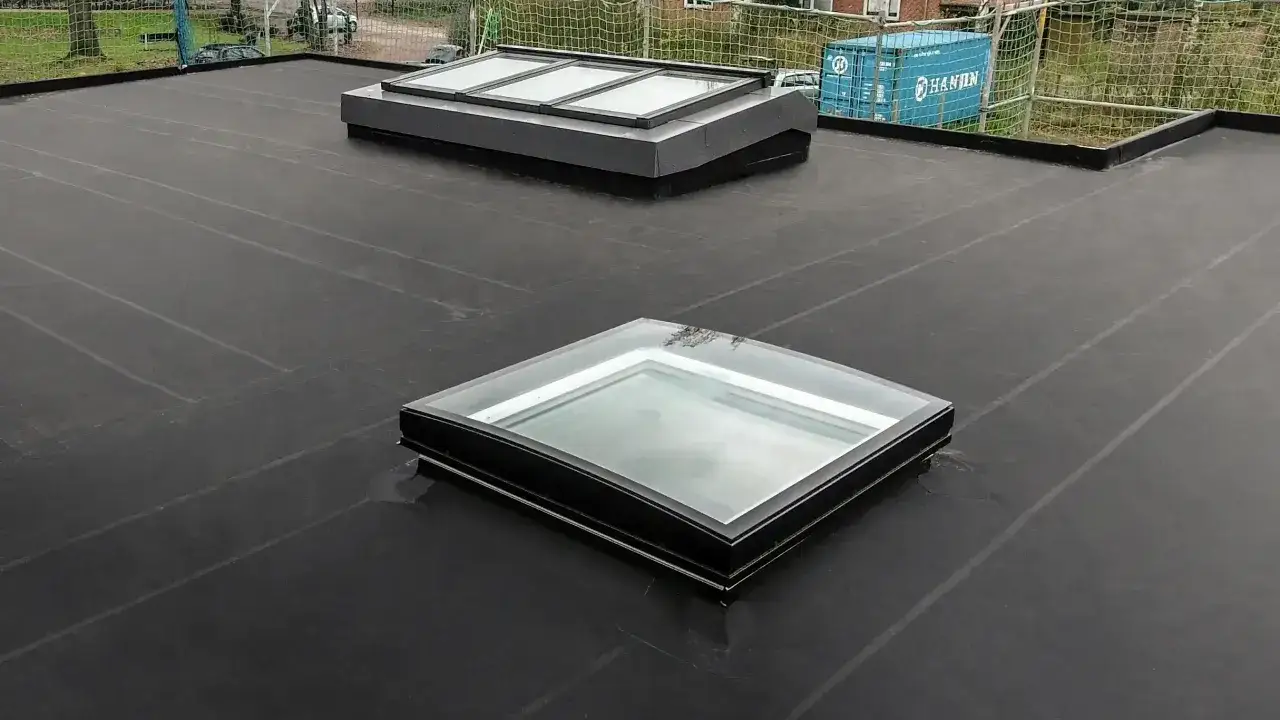 Płaski dach pokryty membraną EPDM, na którym widać dwa świetliki. EPDM co to jest? To trwała i elastyczna guma dachowa.