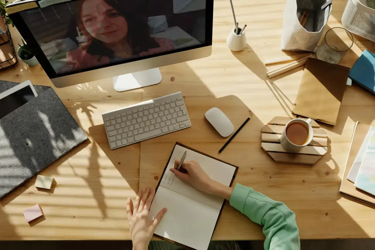 Osoba oglądająca seriale na laptopie z notatkami i słownikiem