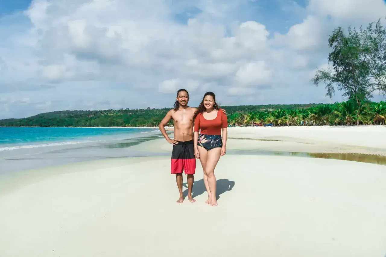 Para na plaży na wyspie Koh Rong w Kambodży, z turkusową wodą i palmami w tle.