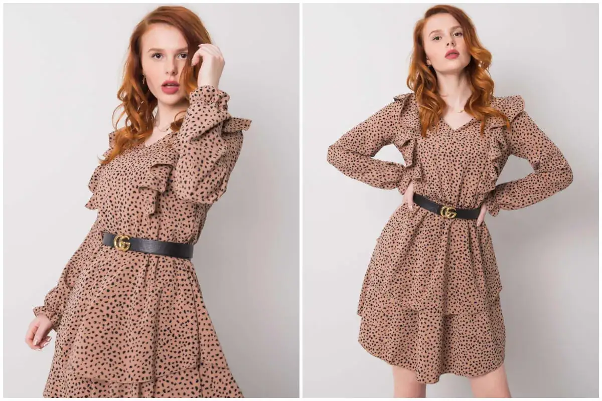 Rudowłosa modelka w beżowej sukience w czarne groszki, z falbankami i czarnym paskiem. Czy groszki są modne? Ta stylizacja sugeruje, że tak!