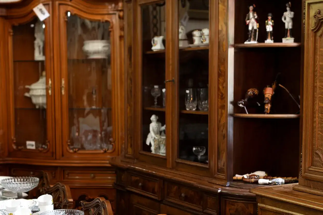 Renowacja mebli PRL: witryny z kryształami, figurkami i fajkami. Drewno w ciepłym odcieniu, ozdobne detale.