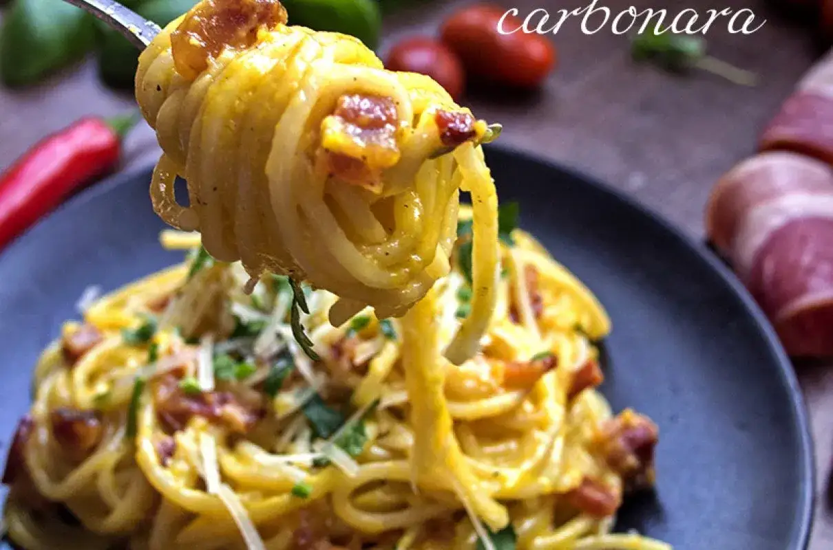 Pyszne spaghetti carbonara na widelcu, z chrupiącym boczkiem i parmezanem. Idealna odpowiedź na pytanie: jaka śmietana do carbonara?