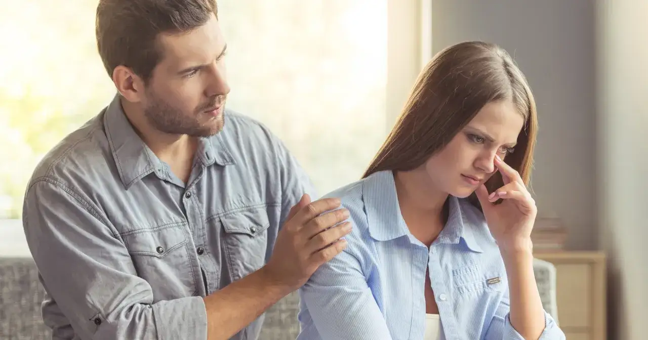 Mężczyzna pociesza smutną kobietę, kładąc jej dłoń na ramieniu. Pokazuje, co napisać po kł&oacute;tni, by załagodzić konflikt.