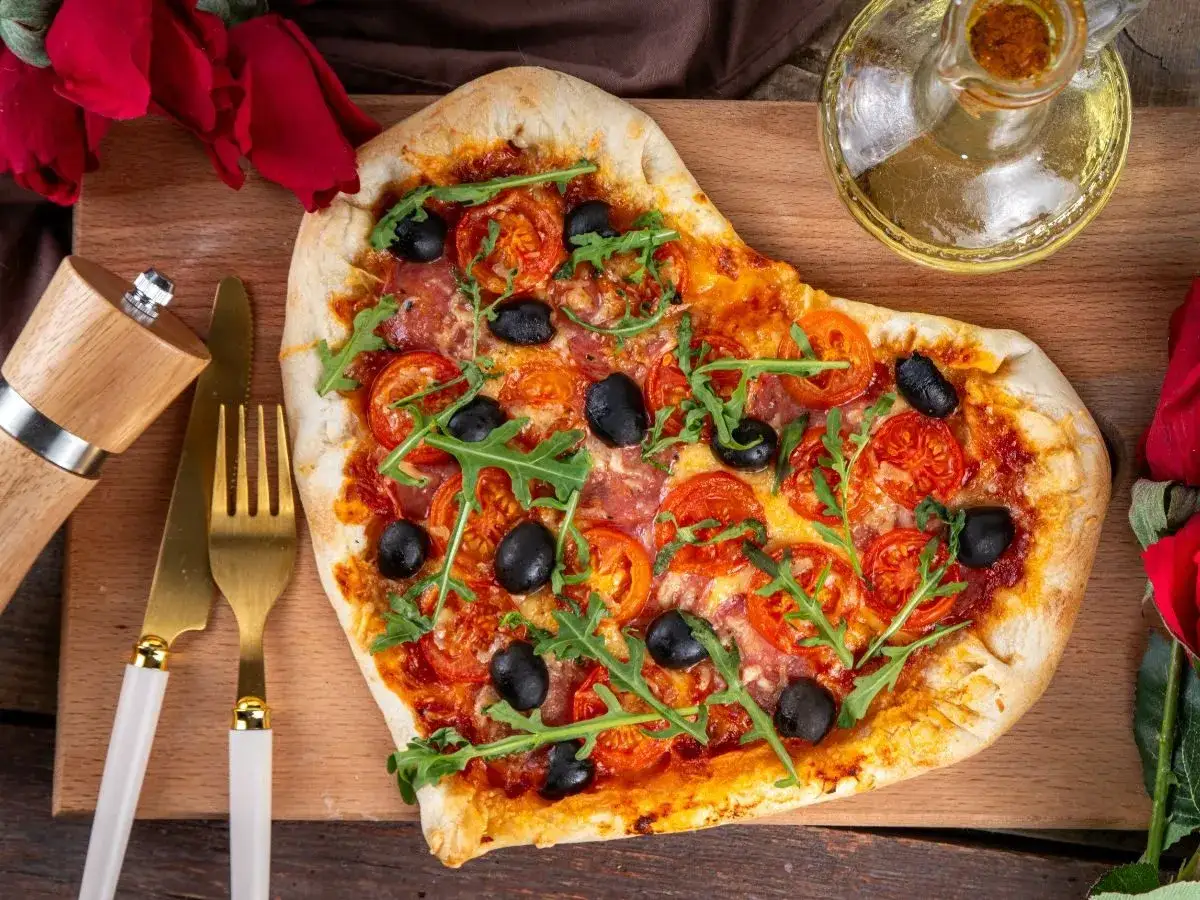 Pizza w kształcie serca z pomidorami, oliwkami i rukolą. Idealna na romantyczną kolację, z dodatkiem oliwy i przypraw.