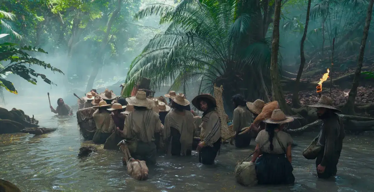 Grupa ludzi w słomkowych kapeluszach przemierza mglistą rzekę w dżungli. Scena z serialu 