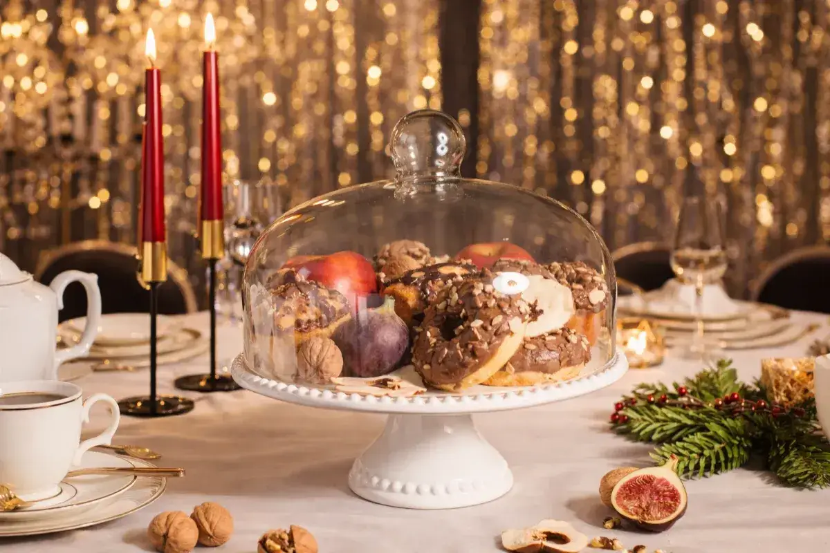 Elegancka patera ceramiczna z ciastkami, owocami i orzechami, przyozdobiona świecami i świątecznymi dekoracjami.