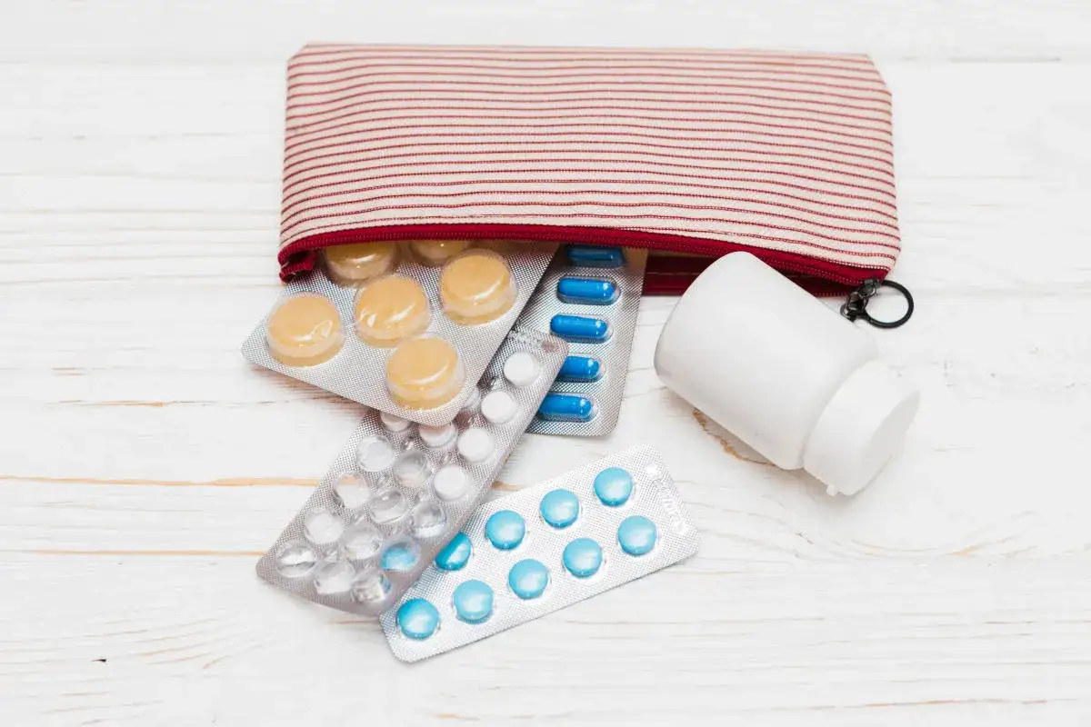 Pigułki w blistrach i biała buteleczka leków obok otwartego etui. Czy można brać leki do samolotu? Tak, ale warto sprawdzić przepisy.