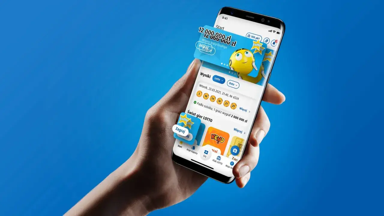 Dłoń trzyma smartfon z aplikacją Lotto, gdzie można sprawdzić zdrapkę i wyniki gier.