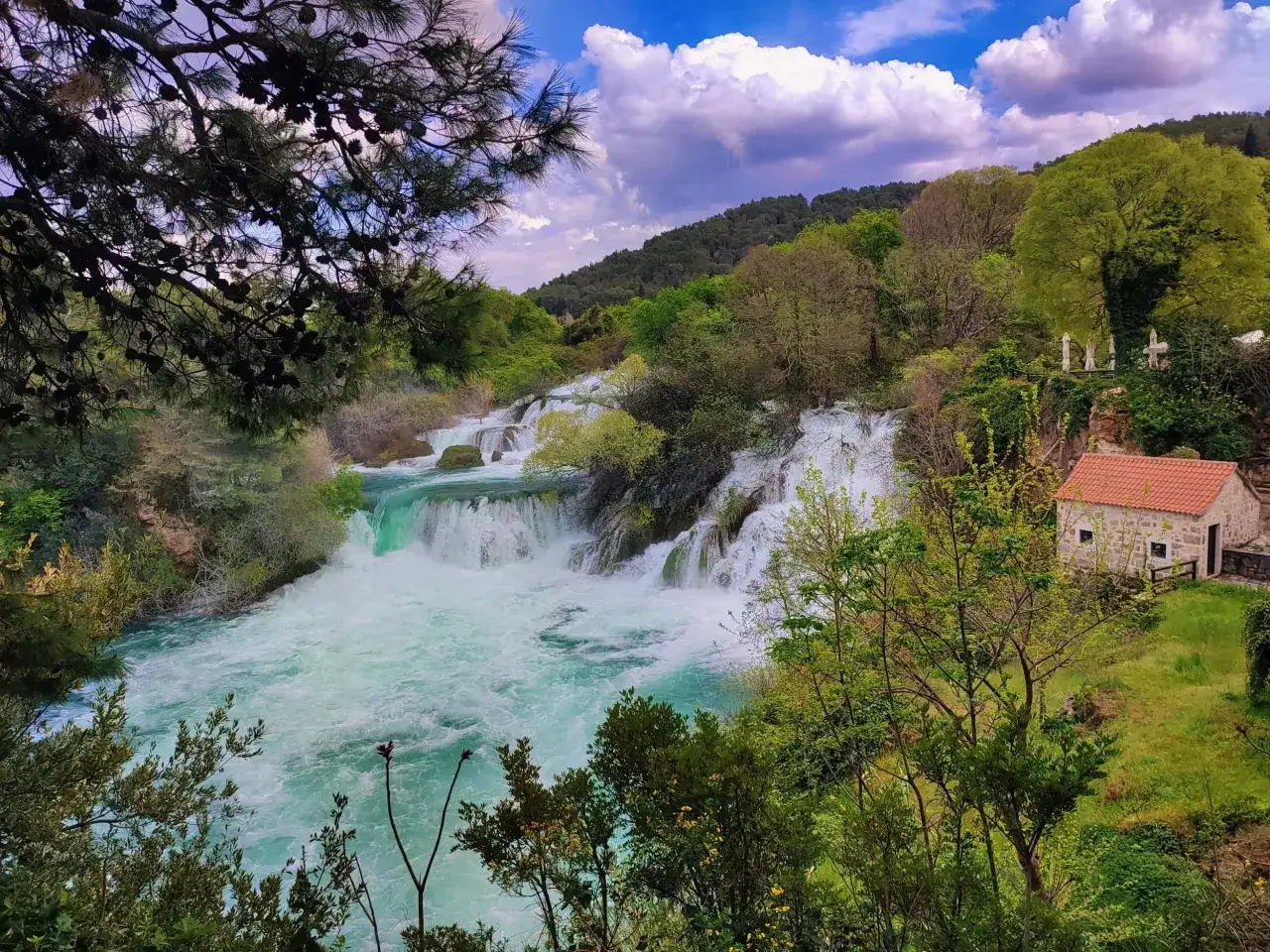 Wodospady w Chorwacji, Szybenik. Turkusowa woda, bujna zieleń i kamienny domek tworzą malowniczy krajobraz.