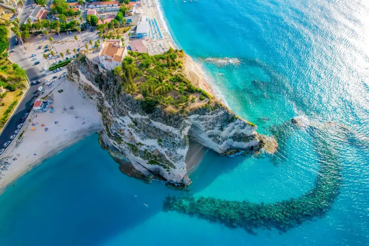 Kalabria co zobaczyć: skaliste wybrzeże z kościołem na szczycie, plaża i turkusowe morze. Idealne miejsce na wakacje.