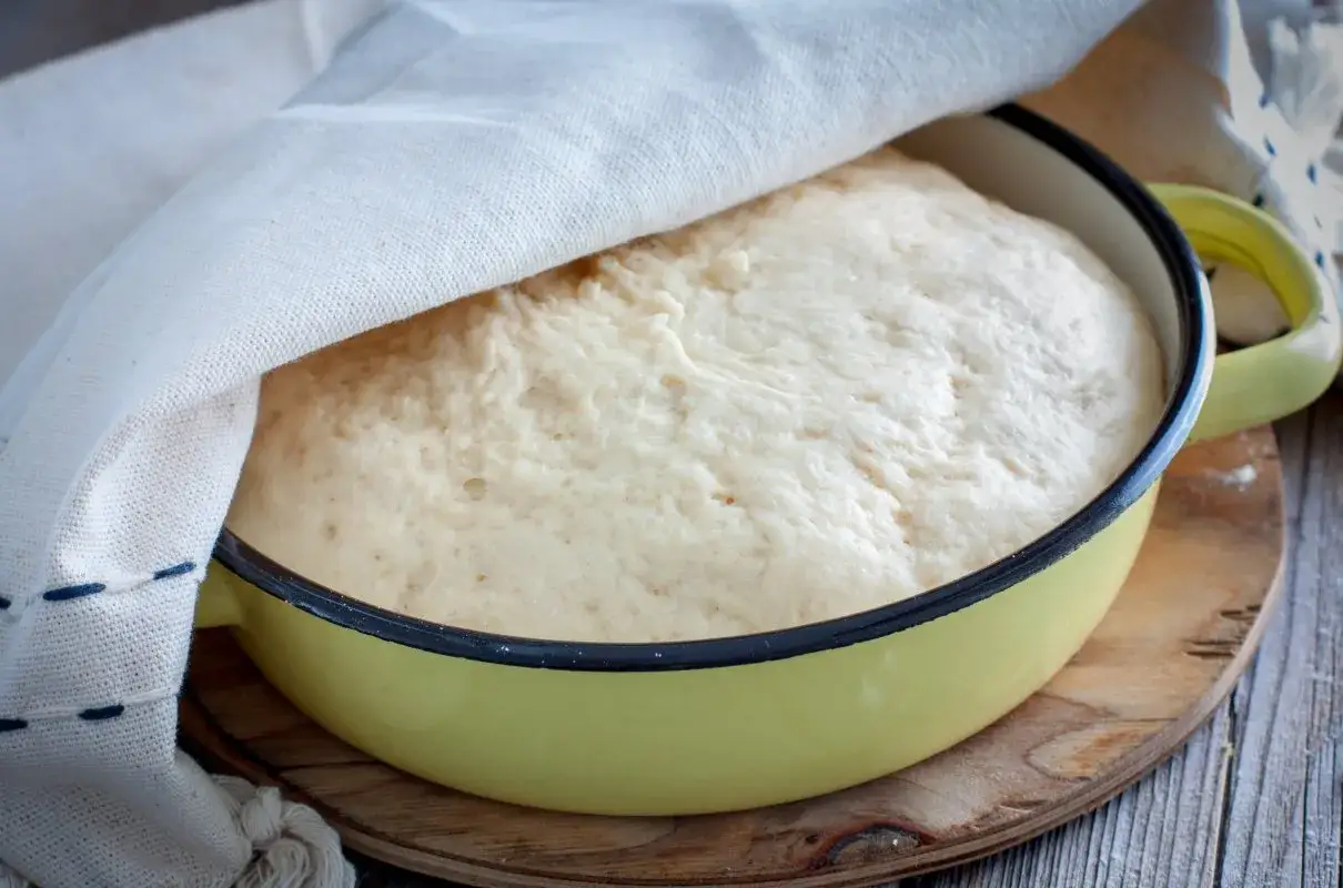 Puszyste ciasto drożdżowe bez wyrabiania Ewy Wachowicz rośnie w żółtej misce pod przykryciem.