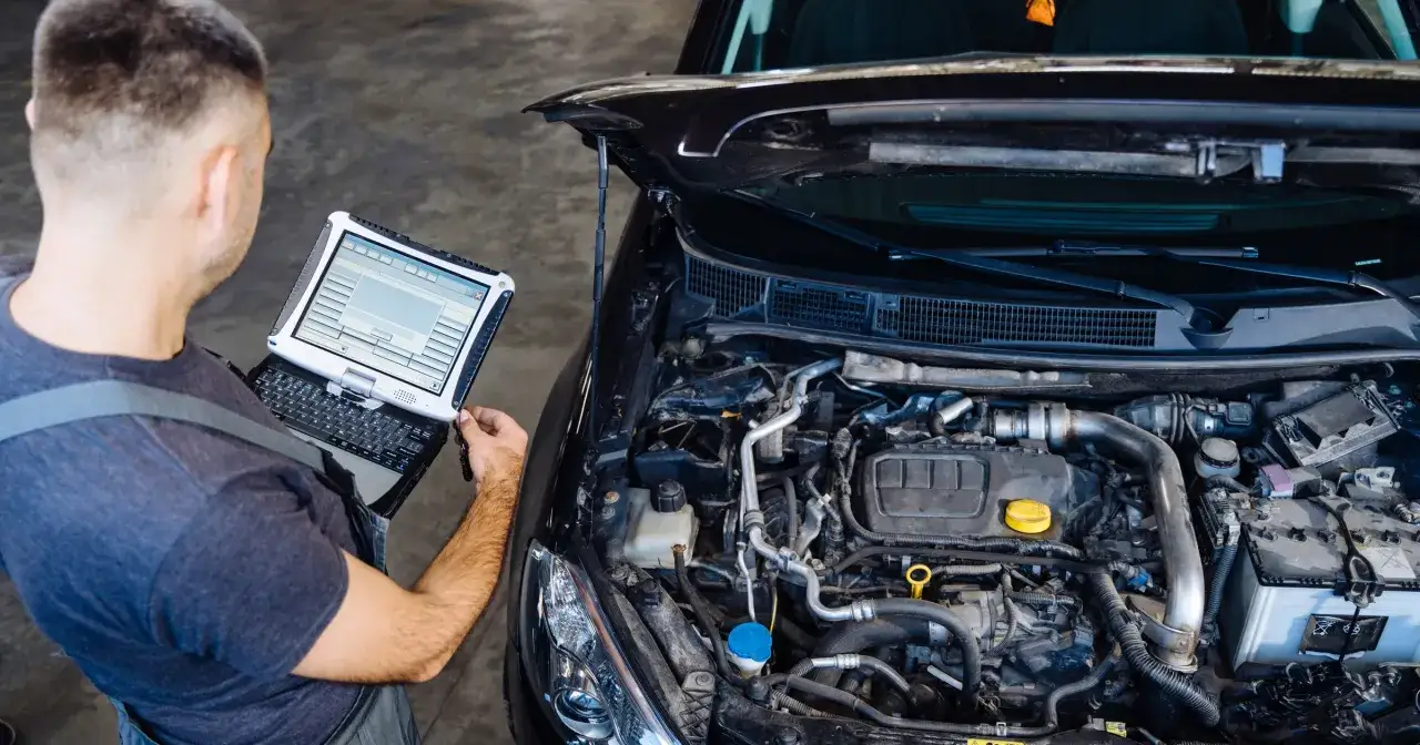 Mechanik z laptopem diagnostycznym przy otwartej masce samochodu. Czy to wyjaśnia, dlaczego od marca 2026 r. ceny roboczogodziny w serwisach ASO skoczyły o 20 proc.?