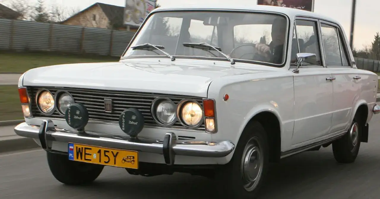 Białe auto zabytkowe, ile lat ma ten klasyk? Widoczny Fiat 125p z lat 70. na drodze.