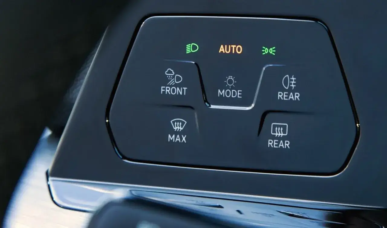 Panel sterowania klimatyzacją z przyciskami: AUTO, FRONT, REAR, MAX. Widać ikonę świateł przeciwmgielnych.