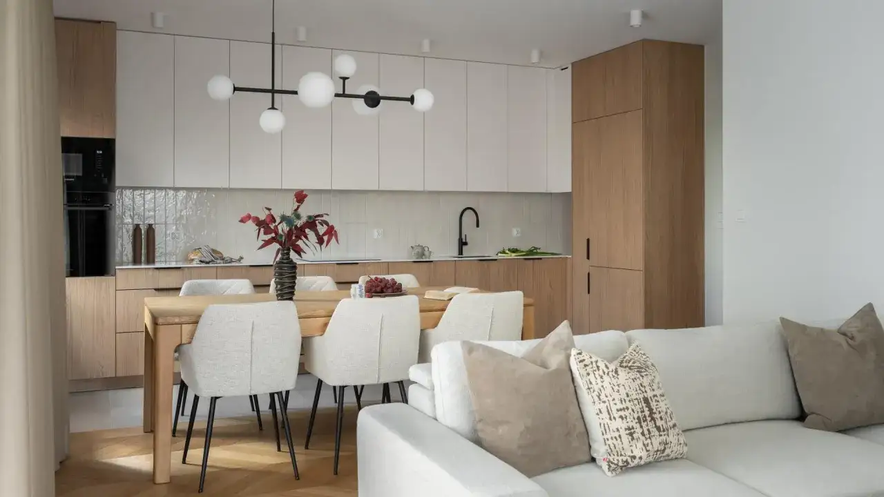 Nowoczesna kuchnia z jadalnią i salonem. Drewniane fronty szafek, jasne meble i minimalistyczny design. Idealne pakiety wykończenia pod klucz.