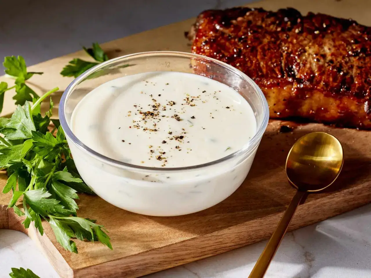 Pyszny sos czosnkowy przepis na grilla. Kremowy sos z ziołami i pieprzem obok soczystego steka.