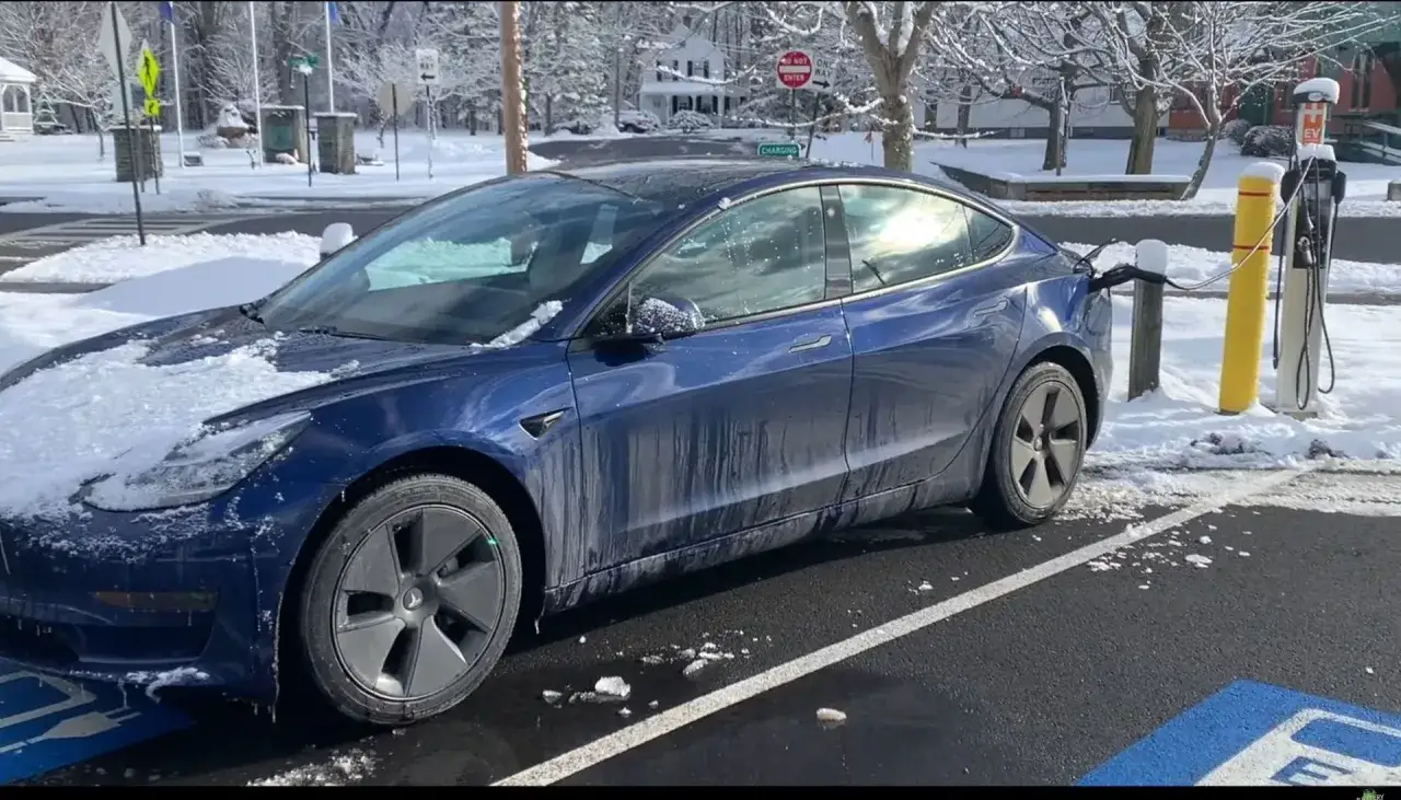 Zimowy dzień, Tesla Model 3 ładuje się na stacji. Ile Tesla ma zasięgu w takich warunkach?
