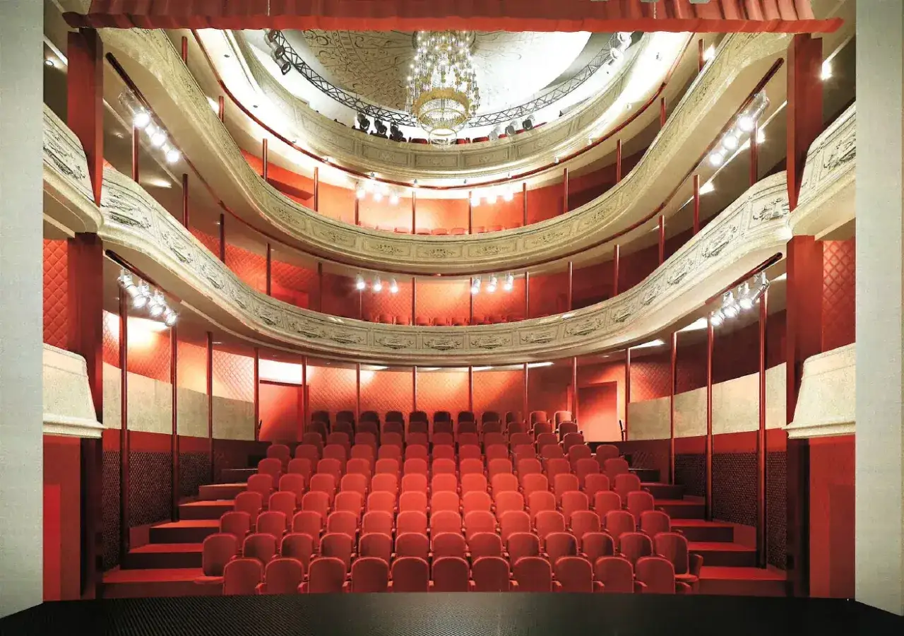 Widok na puste, czerwone fotele w teatrze Osterwy. Widać balkony i żyrandol.