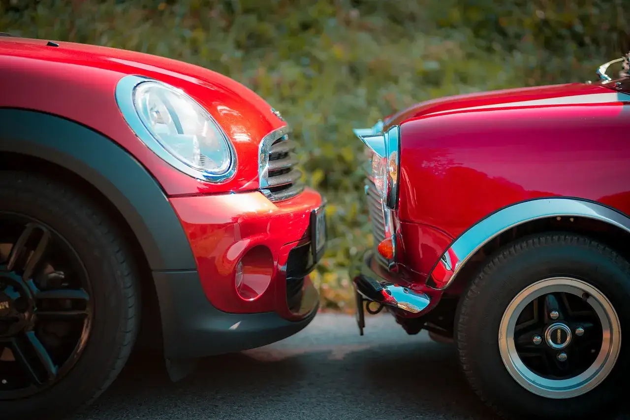 Dwa czerwone samochody Mini Cooper stoją obok siebie, ich błyszczące karoserie odbijają otoczenie.