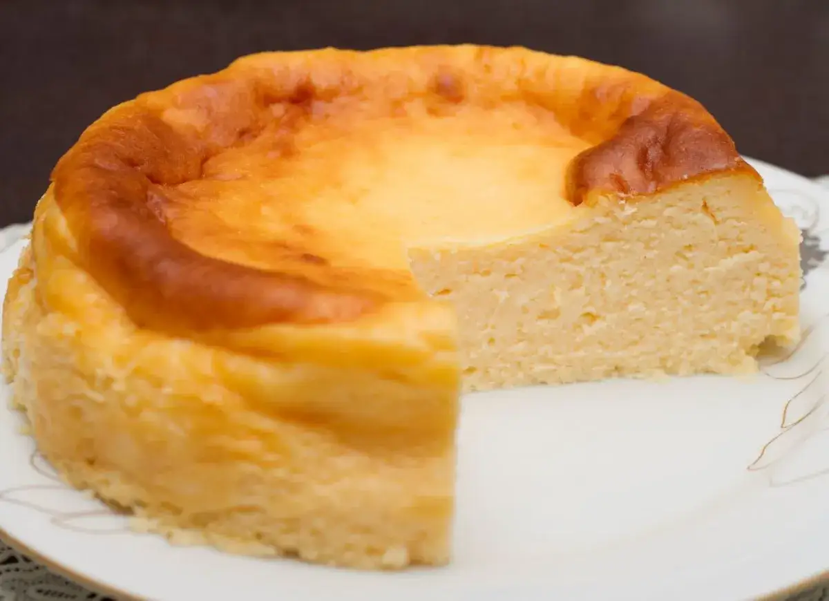 Złocisty sernik na talerzu, z lekko zarumienioną skórką. Wygląda jak najstarszy przepis na sernik, który przetrwał wieki.