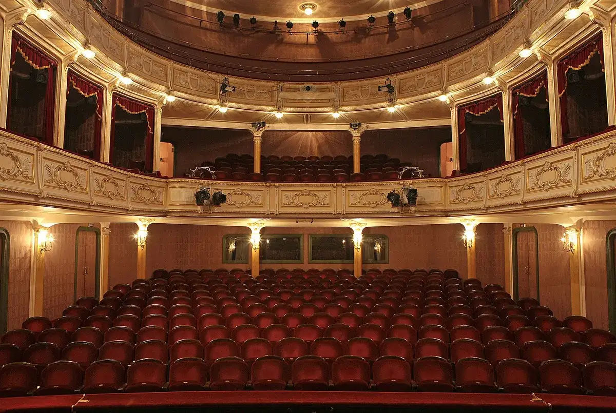 Puste rzędy czerwonych foteli w teatrze. Gdzie najlepiej siedzieć w teatrze? Może na środku, by mieć najlepszy widok?