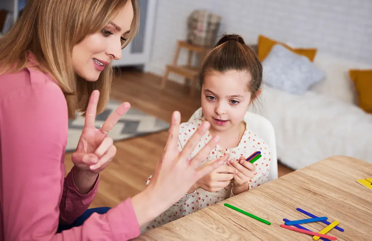 Mama uczy c&oacute;rkę tabliczki mnożenia do 10, używając patyczk&oacute;w.
