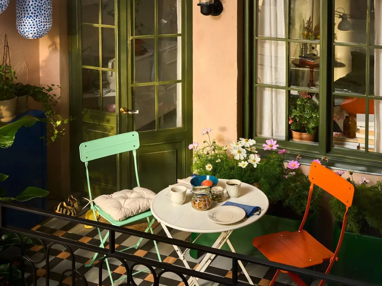 Kolorowy balkon z krzesłami i stolikiem, idealne balkon inspiracje na poranną kawę wśród kwiatów.
