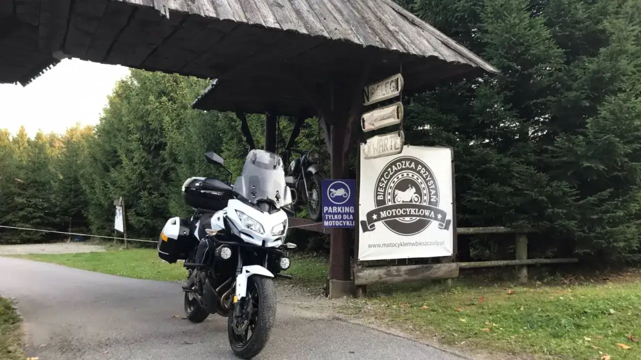 Motocykl czeka na dalszą podróż po pętli bieszczadzkiej. Obok parking dla motocykli i tablica 