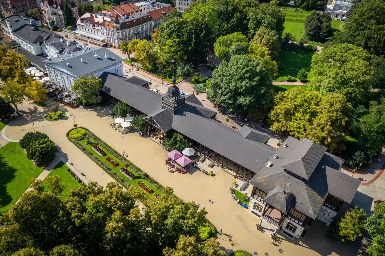 Widok z lotu ptaka na zabytkowe budynki i park w Szczawnie-Zdroju. Widać tu m.in. pijalnię w&oacute;d i tereny zielone, charakterystyczne dla uzdrowiska.