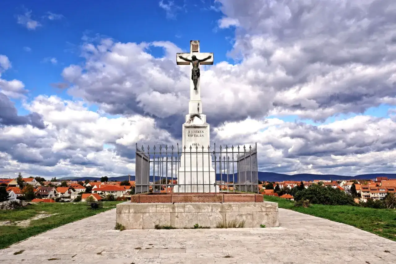 Krzyż na wzgórzu, widok na miasteczko z czerwonymi dachami. To miejsce warto zobaczyć na Węgrzech, oferuje piękne widoki i spokój.
