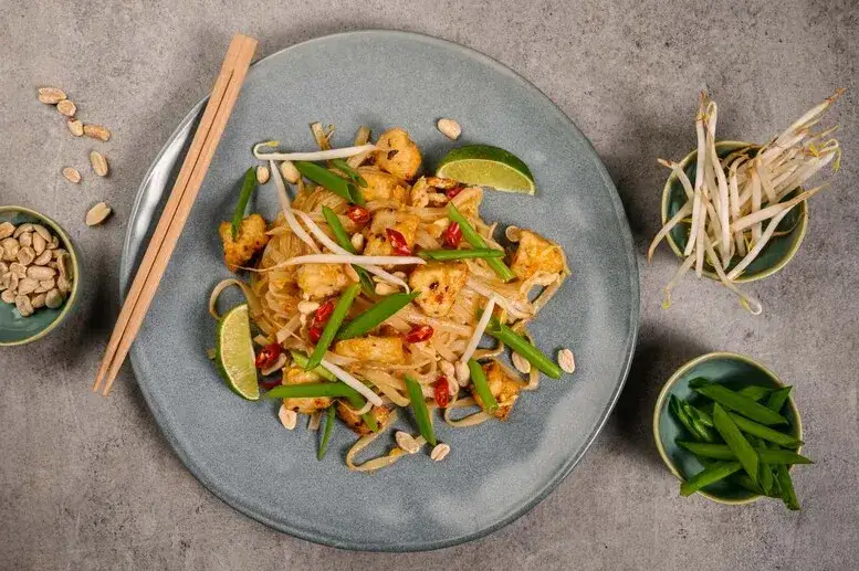 osoba mieszająca Pad Thai z dodatkami